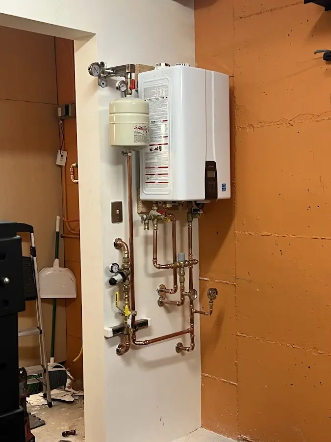 Plumbing technician inspecting water heater connections in Harrison